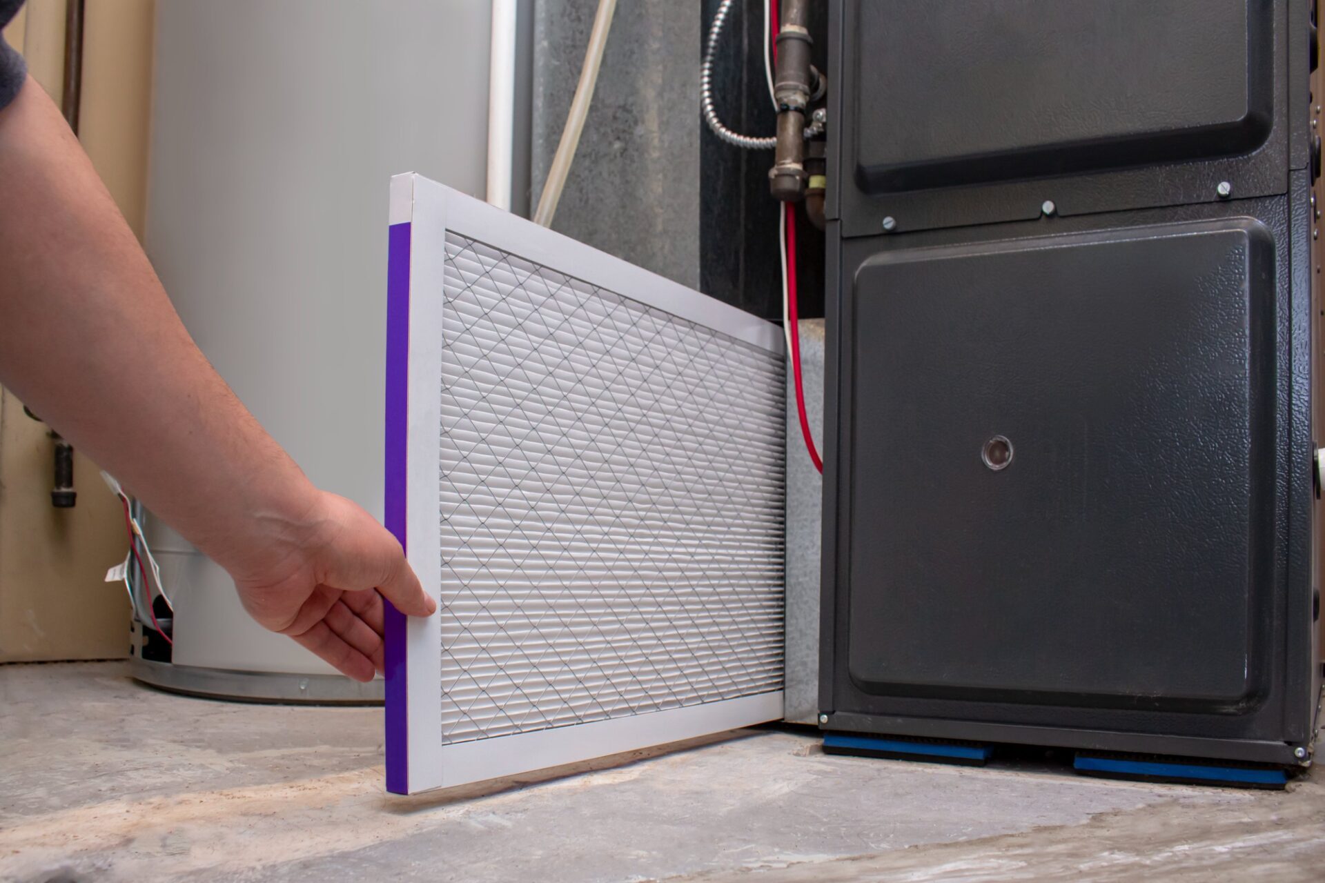 A person changing an clean air filter on a high efficiency furnace